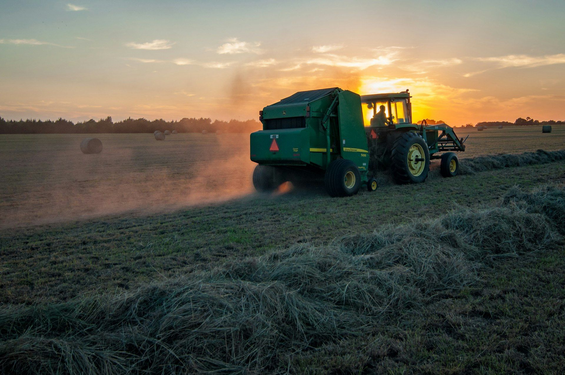 Trattore al lavoro nei campi al tramonto